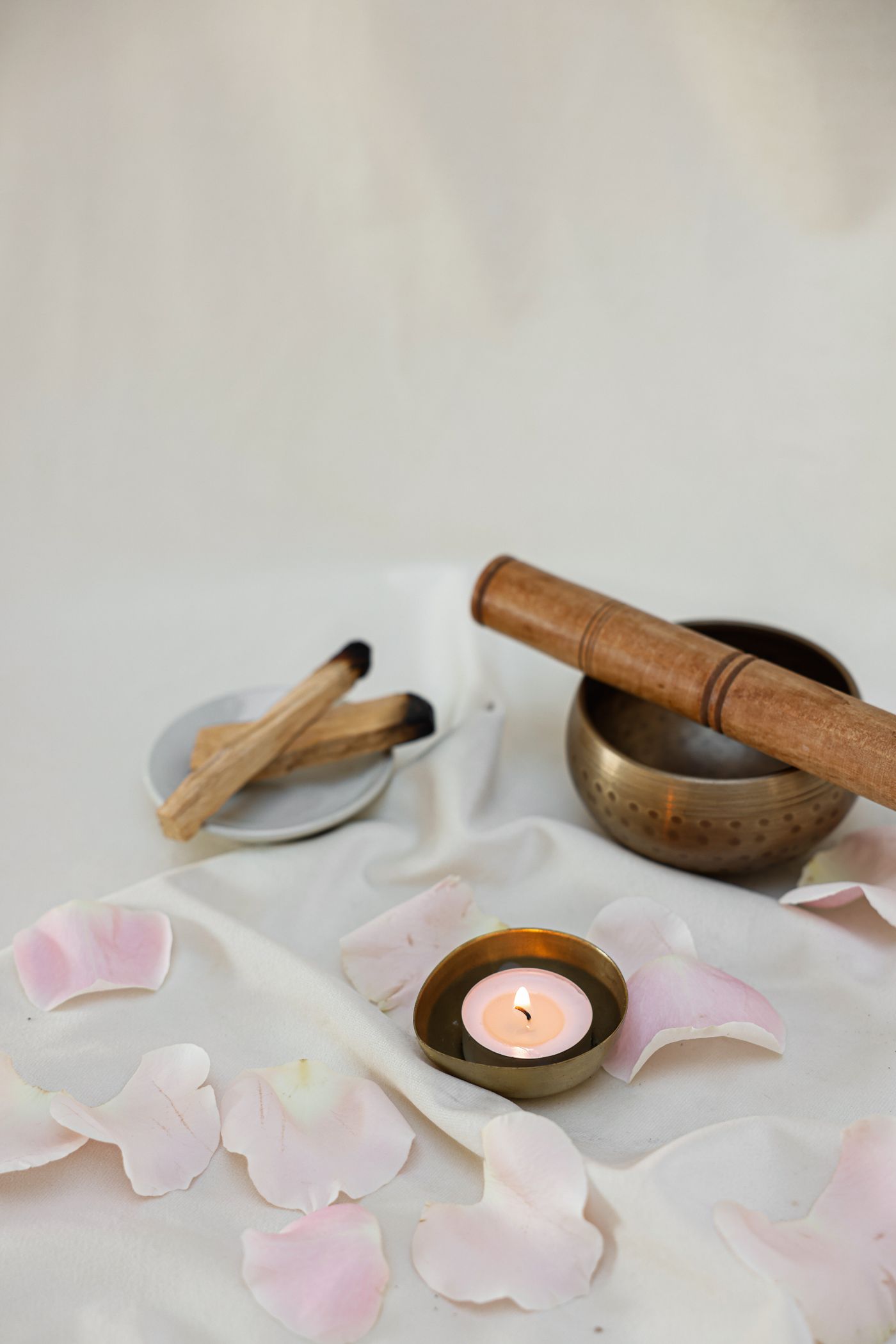 Candle, bowl and petals on pale fabric